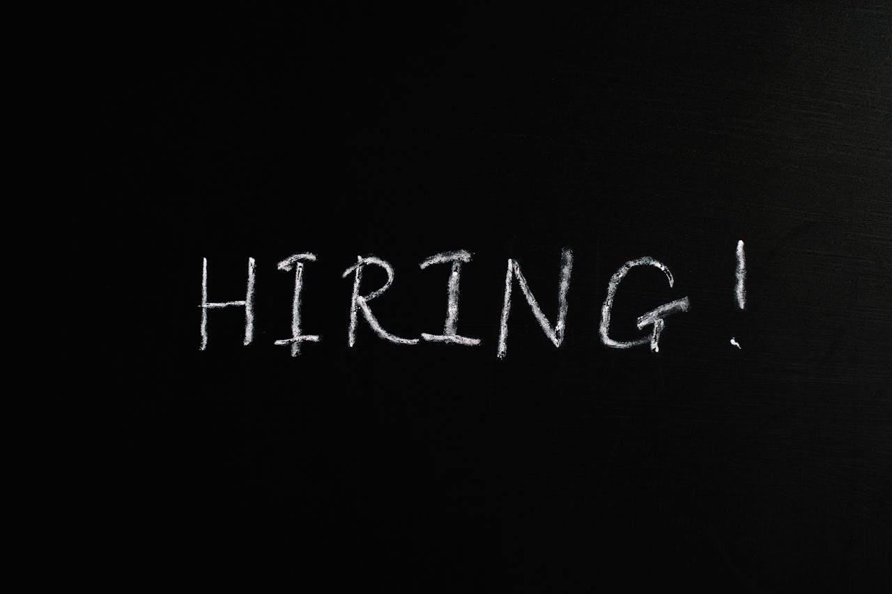 The Art of Drawing Readers In: Your attractive post title goes here Close-up of the word 'Hiring!' written in white chalk on a blackboard, ideal for recruitment themes.
