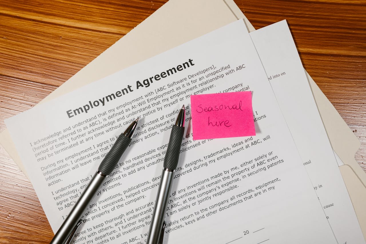 Crafting Captivating Headlines: Your awesome post title goes here Top view of employment agreement contract with pens and seasonal hire note on wooden desk.
